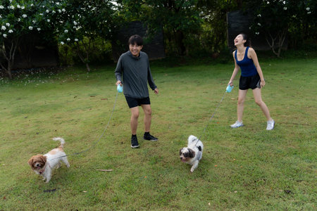 Asian couple walking with their dog in the park in the morning. Friendly pets, a healthy morning...