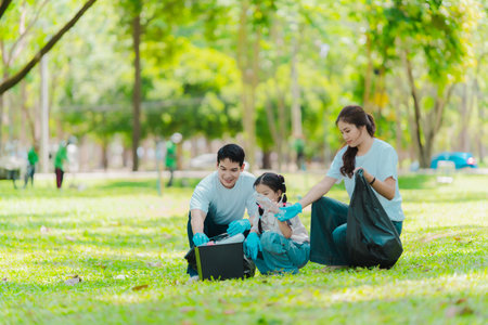 Asian family on summer vacation, parents teaching children to pick up plastic bottles and trash in public park, volunteer concept to protect the environment.の写真素材