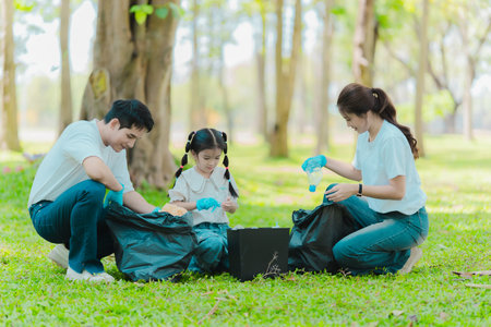 Asian family on summer vacation, parents teaching children to pick up plastic bottles and trash in public park, volunteer concept to protect the environment.の写真素材