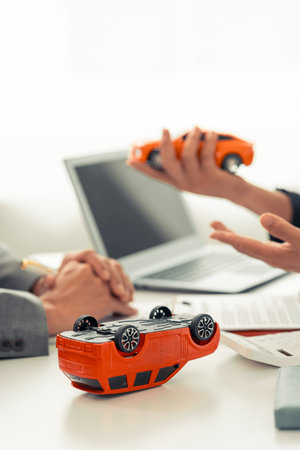 Insurance agent's hand protecting red toy car on table. Planning to manage transportation finance cost. Car insurance business concept.の写真素材