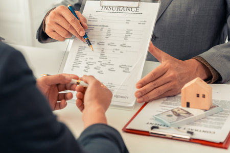 The real estate agent discussed the terms of the home purchase contract and asked the client to sign the document to legally complete the contract.の写真素材