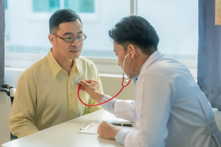 Doctor sitting on chair checking heart rate of asian senior man medical concept doctor examining patient with stethoscope during consultation in hospitalの写真素材