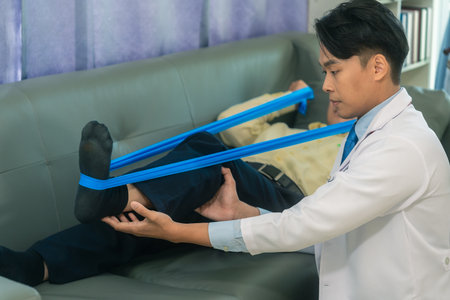 Male doctor diagnoses male patient's leg by pressing on his leg, foot bone close up, doctor helps physical therapy for old manの写真素材