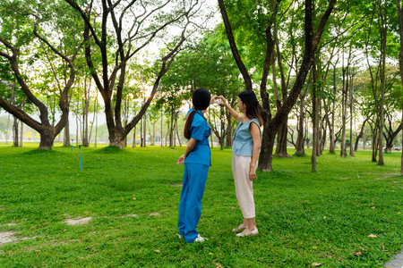 Asian female doctor takes care of elderly female patient in the park, helps the patient walk and exercises her legs and knees in the park.の写真素材
