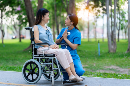 Caregiver takes elderly in wheelchair to walk in the park for health therapy, insurance concept for the elderly, happy retirementの写真素材