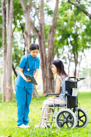 Caregiver takes elderly in wheelchair to walk in the park for health therapy, insurance concept for the elderly, happy retirementの写真素材