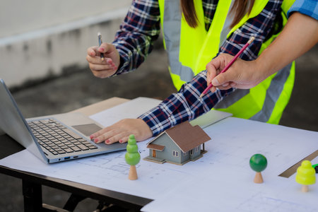 Engineers working on meeting blueprints to collaborate on projects with partners to create models and engineering tools on-site.の写真素材