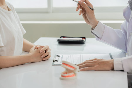 An orthodontist demonstrates a model of a patient's teeth. The dentist explains techniques for cleaning, examining, and maintaining oral health. Close-up view.の写真素材