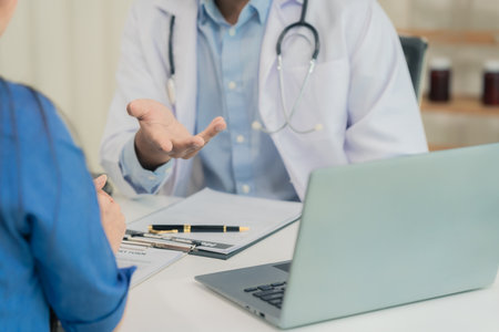 Doctor and patient are discussing various topics while sitting at a table. Concept of medicine and healthcare. Doctor shows clipboard with information for patient.の写真素材