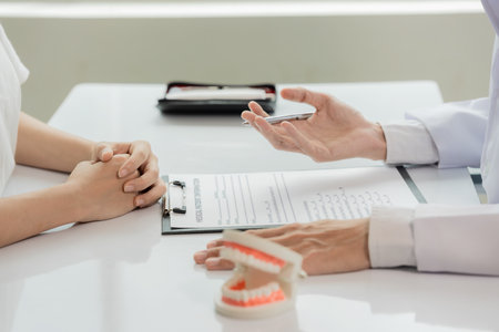 An orthodontist demonstrates a model of a patient's teeth. The dentist explains techniques for cleaning, examining, and maintaining oral health.の写真素材