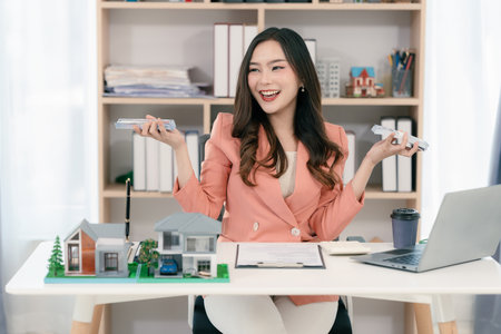 Excited young Asian real estate agent sells her house for investment and offers business and finance presentations.の写真素材
