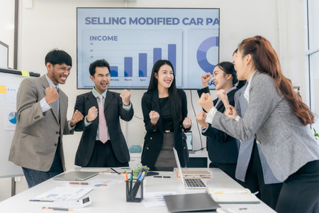 Group of happy Asian businesspeople congratulating each other to celebrate success in office...