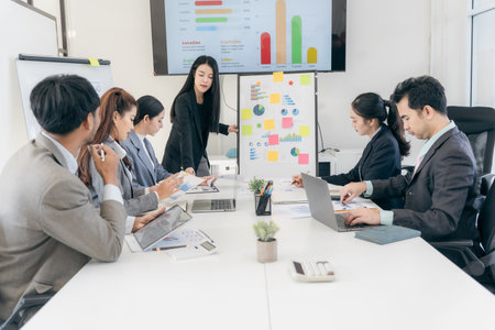 Group of business people discussing charts and graphs showing successful teamwork. Asian business...