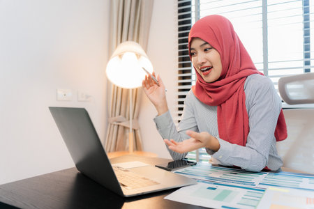 Businesswoman wearing hijab working with laptop in office. Muslim woman working with documents and...