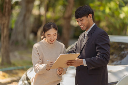 A modern car dealer explains car features to a female customer during the car purchase process, emphasizing professional customer service. Interaction during car sales.の写真素材