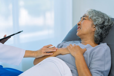 Doctor is examining elderly female patient in ward while doctor is checking her condition in recovery room. Medical and healthcare concept.の写真素材