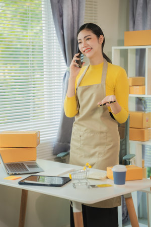 Portrait of young Asian woman using mobile phone, online shopping concept for SME entrepreneurs or freelancers, young small business entrepreneurs working with smartphone at home.の写真素材