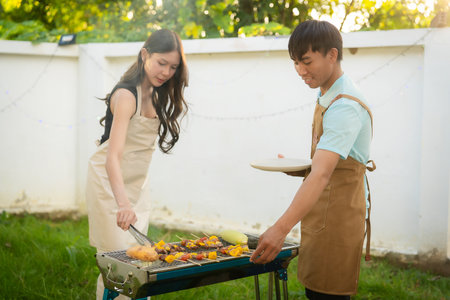 A group of friends of different nationalities are having a backyard dinner party, toasting beers or sharing drinks during happy hour. Young people are having fun together, toastingの写真素材