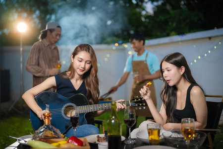 A group of multiracial friends are having a backyard dinner party, clinking drinks during happy hour. Young people are having fun together and clinking drinks whileの写真素材