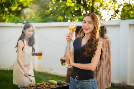 A group of friends of different nationalities are having a backyard dinner party, toasting beers or sharing drinks during happy hour. Young people are having fun together, toastingの写真素材
