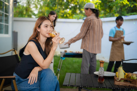 A group of friends of different nationalities are having a backyard dinner party, toasting beers or sharing drinks during happy hour. Young people are having fun together, toastingの写真素材