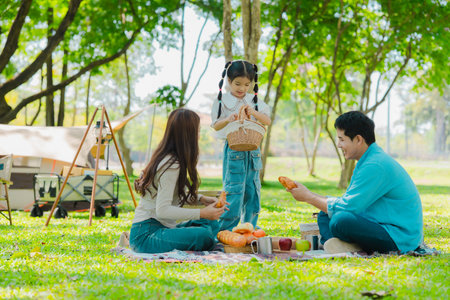 Happy Asian family having a picnic in the park during summer vacation. The boy enjoys his trip with his parents in the park. Beautiful nature.の写真素材