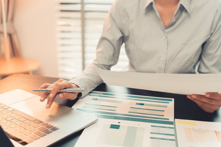 Businesswoman hands holding pen working with charts and graphs showing work success, financial report analysis, planning strategy and performance. Close up.の写真素材