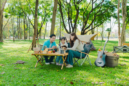 Happy Asian family having a picnic in the park during summer vacation. The boy enjoys his trip with his parents in the park. Beautiful nature.の写真素材