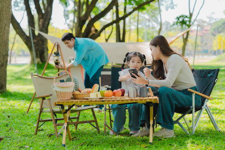 Happy Asian family having a picnic in the park during summer vacation. The boy enjoys his trip with his parents in the park. Beautiful nature.の写真素材