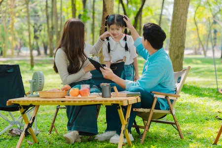 Happy Asian family having a picnic in the park during summer vacation. The boy enjoys his trip with his parents in the park. Beautiful nature.の写真素材