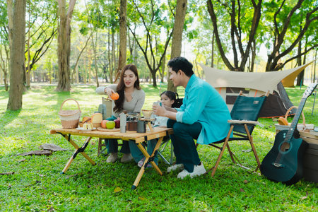 Happy Asian family having a picnic in the park during summer vacation. The boy enjoys his trip with his parents in the park. Beautiful nature.の写真素材