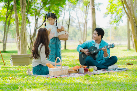 Happy Asian family having a picnic in the park during summer vacation. The boy enjoys his trip with his parents in the park. Beautiful nature.の写真素材