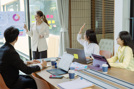 Group of Asian business people presenting data to colleagues in conference room. Business people in...