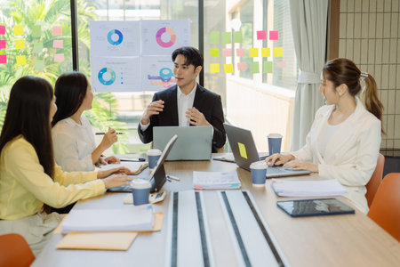 Group of Asian business people presenting data to colleagues in conference room. Business people in...