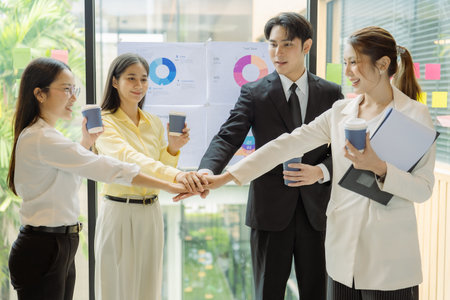 Business people shaking hands while female colleagues stand applauding at wooden table congratulating new project contract plan ready for happy working in company office.の写真素材