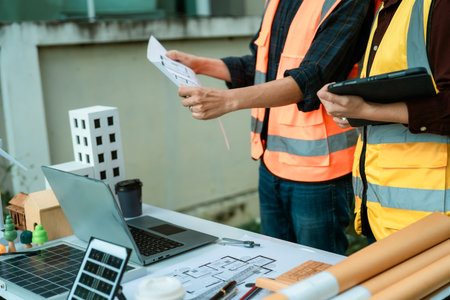 Two young engineers, experts in solar cell installation, meeting and discussing at the factory building, planning the installation of solar panels on the roof.の写真素材