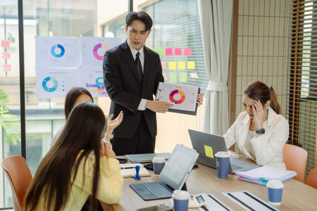 Group of Asian business people presenting data to colleagues in conference room. Business people in...