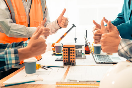 Close-up of engineer and architect shaking hands after completion of agreement, between construction workers wearing safety vests, teamwork cooperation on construction site.の写真素材