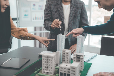 A group of young Asian businesspeople meet at an office for a residential real estate project. A...