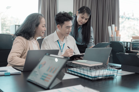 Group of business people discussing charts and graphs showing results of teamwork of colleagues working together at desks in office and discussing documents.の写真素材