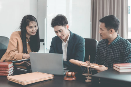 A serious lawyer discussing legal documents will examine important documents during a serious consultation, with the hammer and scales that are the hallmarks of justice.の写真素材