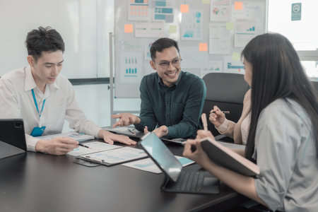 Group of business people discussing charts and graphs showing results of teamwork of colleagues working together at desks in office and discussing documents.の写真素材