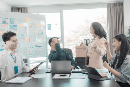 Group of successful Asian businesspeople smiling and laughing, posing and making gestures of joy together in a company office conference room.の写真素材