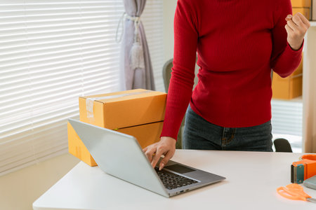 Small business owners working with laptops at home for ecommerce, SME startups, entrepreneurs working with receipt boxes and checking online orders.の写真素材