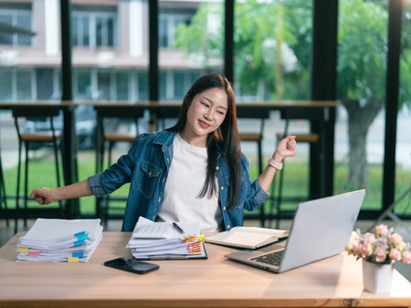 Professional employees feel relaxed while doing stretching exercises, relieving stress from working on laptop computers in the office.の写真素材