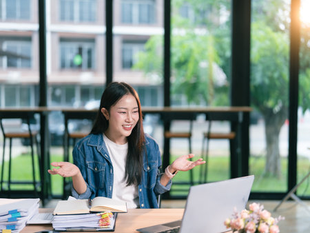 Asian businesswoman happy with her job enjoying working with laptop computer and financial documents in officeの写真素材