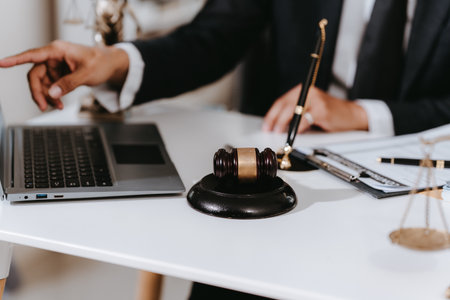 Lawyer, man giving advice to client at table with scales and gavel. Lawyer handing document and pen to client. Legal services concept. Close up.の写真素材