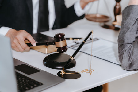 Lawyer, man giving advice to client at table with scales and gavel. Lawyer handing document and pen...