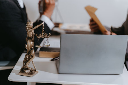 Lawyer giving advice to client at table with scales and gavel. Lawyer handing document and pen to...