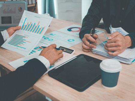 Business people discuss charts and graphs that show the results of teamwork, effective data analysis, and the success of the finance department's planning.の写真素材